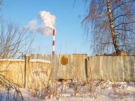 Factory pipe. Industrial zone. Icicles on the roof. Fence. photo