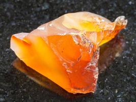 rough Carnelian chalcedony gemstone on dark photo