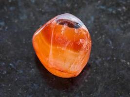 tumbled carnelian gem stone on dark background photo