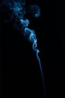 un disparo vertical de humo de tabaco azul sobre un fondo negro foto