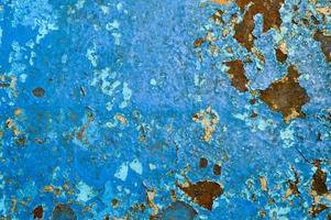 The texture of the iron metal painted blue paint old battered scratched cracked ancient rusty metal sheet wall with corrosion. The background photo