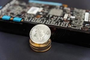 Cryptocurrency golden silver bitcoin coin lying on video card. Electronic virtual money for web banking and international network payment. Symbol of crypto virtual currency. Mining concept. photo