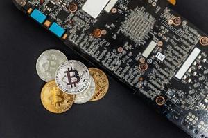 Cryptocurrency golden silver bitcoin coin lying on video card. Electronic virtual money for web banking and international network payment. Symbol of crypto virtual currency. Mining concept. photo