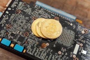 Cryptocurrency golden bitcoin coin lying on video card. Electronic virtual money for web banking and international network payment. Symbol of crypto virtual currency. Mining concept. photo
