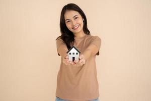 Happy young woman holding a house model standing in the studio photo