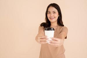 Happy young woman holding coffee cup standing in the studio photo