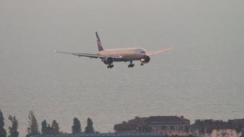 SOCHI, RUSSIA JULY 30, 2022 - Slow motion, Boeing 777 of Aeroflot approaching before landing in Sochi airport at dawn. Airliner flies over the sea and over the city. Tourism and travel concept video