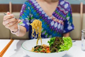 Hand holding fork eating spaghetti in restaurant. photo