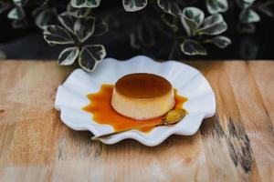 White plate of delicious caramel custrad on wooden table. photo