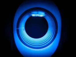 The circular tunnel has a blue neon glow in the dark. photo