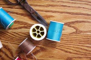 Multicolored threads and old scissors scattered on a wooden table, retro scissors, flat lay, copy space. photo