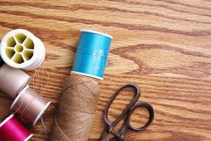 Multicolored threads and old scissors scattered on a wooden table, retro scissors, flat lay, copy space. photo