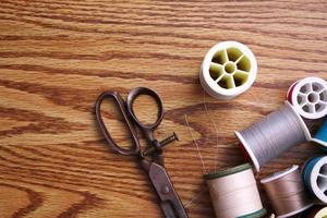 Multicolored threads and old scissors scattered on a wooden table, retro scissors, flat lay, copy space. photo