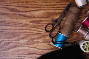 Multicolored threads and old scissors scattered on a wooden table, retro scissors, flat lay, copy space. photo