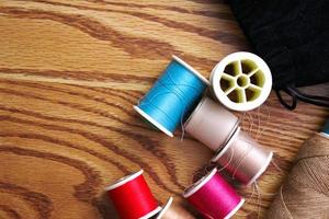 Multicolored threads and old scissors scattered on a wooden table, retro scissors, flat lay, copy space. photo