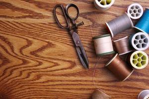 Multicolored threads and old scissors scattered on a wooden table, retro scissors, flat lay, copy space. photo