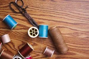 Multicolored threads and old scissors scattered on a wooden table, retro scissors, flat lay, copy space. photo