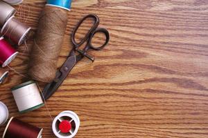 Multicolored threads and old scissors scattered on a wooden table, retro scissors, flat lay, copy space. photo