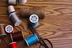 Multicolored threads and old scissors scattered on a wooden table, retro scissors, flat lay, copy space. photo