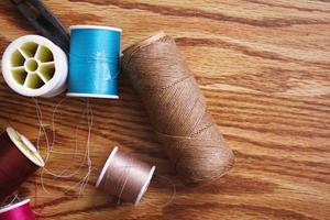 Multicolored threads and old scissors scattered on a wooden table, retro scissors, flat lay, copy space. photo