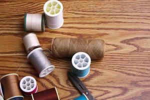 Multicolored threads and old scissors scattered on a wooden table, retro scissors, flat lay, copy space. photo