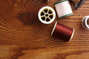 Multicolored threads and old scissors scattered on a wooden table, retro scissors, flat lay, copy space. photo