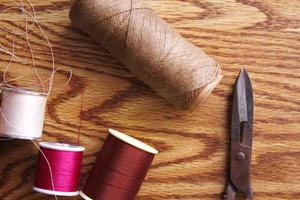Multicolored threads and old scissors scattered on a wooden table, retro scissors, flat lay, copy space. photo