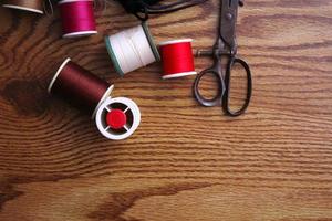 Multicolored threads and old scissors scattered on a wooden table, retro scissors, flat lay, copy space. photo