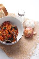 Spicy Stir Fried Catfish served in a Thai style patterned bowl on a white table. photo