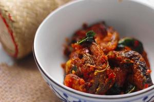 Spicy Stir Fried Catfish served in a Thai style patterned bowl on a white table. photo