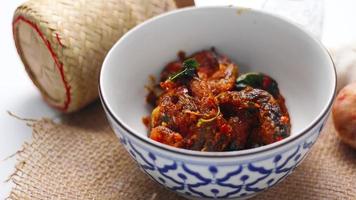 Spicy Stir Fried Catfish served in a Thai style patterned bowl on a white table. photo