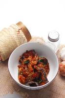 Spicy Stir Fried Catfish served in a Thai style patterned bowl on a white table. photo