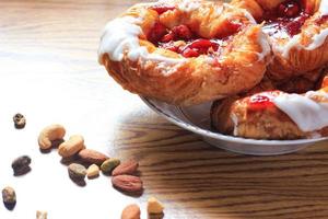 Cherry filled Danish or Danish bread served in a white plate on a brown wooden table. photo