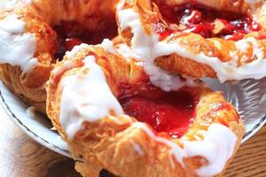 Cherry filled Danish or Danish bread served in a white plate on a brown wooden table. photo