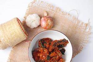 Spicy Stir Fried Catfish served in a Thai style patterned bowl on a white table. photo