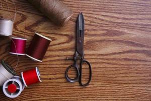 Multicolored threads and old scissors scattered on a wooden table, retro scissors, flat lay, copy space. photo