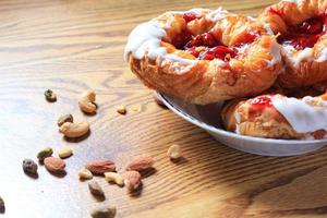 Cherry filled Danish or Danish bread served in a white plate on a brown wooden table. photo