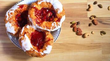 Cherry filled Danish or Danish bread served in a white plate on a brown wooden table. photo