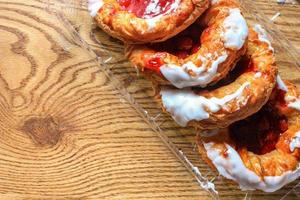 Cherry filled Danish or Danish bread in a plastic box placed on a brown wooden table. photo