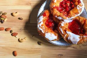 Cherry filled Danish or Danish bread served in a white plate on a brown wooden table. photo