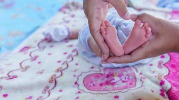 Parents hands holding small newborn baby girl feet. photo