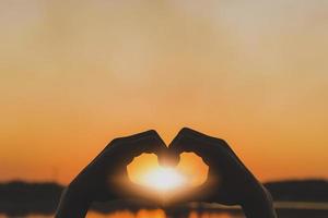 Silhouette love symbol heart symbol hand in the evening sunset. photo