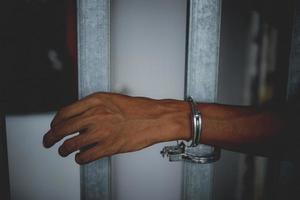 Hand of the prisoner on a steel lattice close up photo