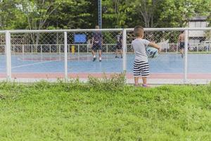 niño sosteniendo una pelota de fútbol en la mano en un campo de fútbol los niños pequeños quieren jugar al fútbol. foto