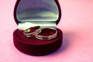 A beautiful red festive gift box velvet for two engagement, wedding rings with precious gold round precious pile rings. Concept marriage proposal, wedding, engagement photo