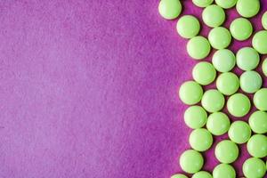 Small yellow orange beautiful medical pharmaceptic round pills, vitamins, drugs, antibiotics on a pink purple background, texture. Concept medicine, health care. Flat lay, top view photo