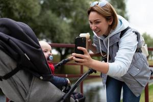 madre joven muestra a un niño en una caricatura de cochecito en el teléfono foto