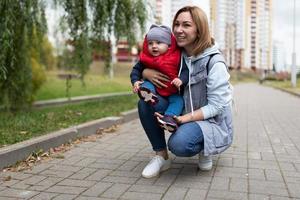 la joven madre se sentó con un niño pequeño durante un paseo por la calle con una sonrisa mirando la cámara foto