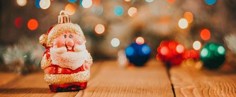 Christmas background with gift boxes, santa claus toy on wooden background with garland bokeh. Festive winter concept. photo