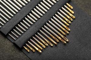 Set of Gold needles on a black background in a row. photo